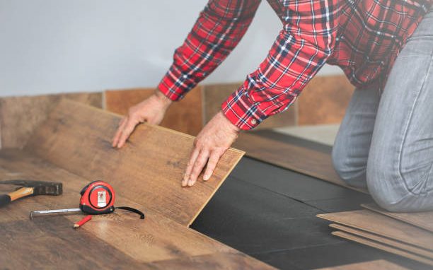Craftsman installing new hardwood flooring in a renovated room